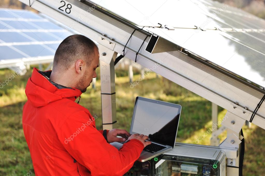 Tecnico che controlla un quadro elettrico vicino a pannelli solari